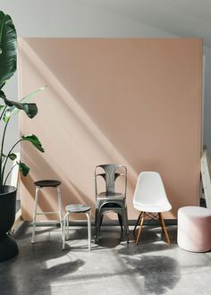 several chairs and stools in front of a pink wall