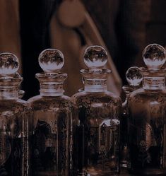 three glass jars sitting next to each other on top of a wooden table in front of a mirror