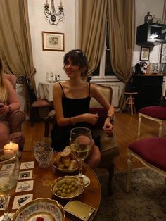 two women sitting at a table with food and wine