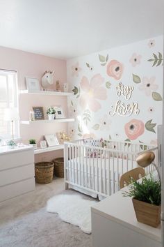 a baby's room with pink and white flowers on the wall