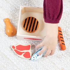 a child's hand holding scissors next to an animal shaped cookie and other toys