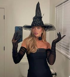 a woman wearing a witches hat and holding a cell phone