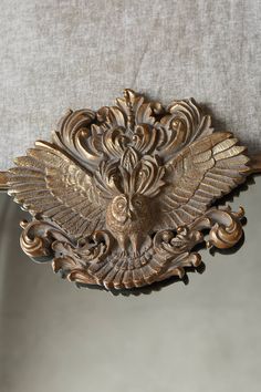 an ornately carved wooden handle on a chair with a gray background and white linen