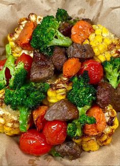 a bowl filled with meat, vegetables and corn on top of brown paper bag wrappers