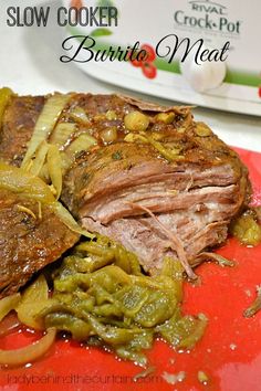 slow cooker burrito meat with peppers and onions on a red cutting board next to a plate