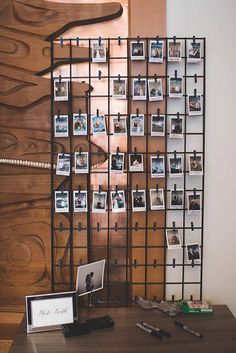 a wooden table topped with a laptop computer next to a metal rack filled with photos