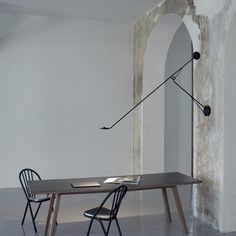 an empty room with a table and two chairs in front of a wall that has been painted white