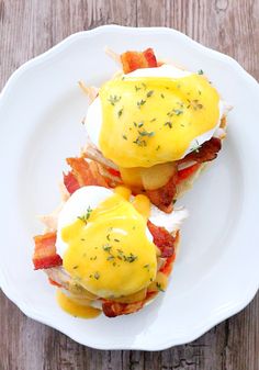 two eggs benedicts with bacon on a white plate