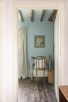 an open door leading to a room with blue walls and wood flooring in it