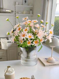 a vase filled with pink and white flowers on top of a table next to a pie