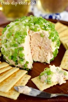 a cheese ball filled with meat and veggies on a wooden platter next to crackers