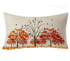 an embroidered pillow with trees and birds in autumn colors on the front, sitting on a white background