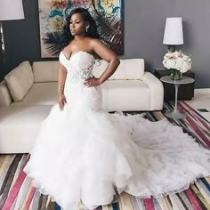 a woman in a white wedding dress standing on a colorful rug next to a couch