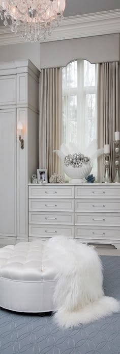 a bedroom with white furniture and chandelier