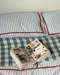 a stack of magazines sitting on top of a blue and white checkered bedspread