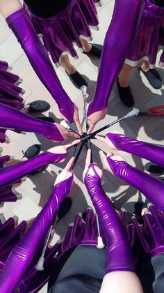 several people in purple outfits are holding their hands together