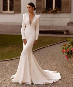 a woman in a white wedding dress standing outside