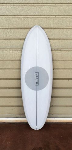 a white surfboard leaning up against a wall