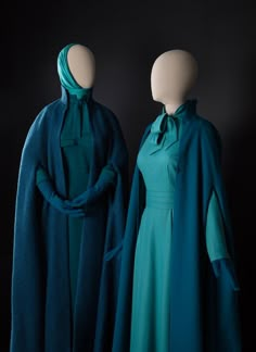 two mannequins dressed in teal clothing with scarves on their heads