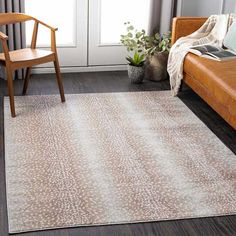 a living room area with a couch, chair and rug on the floor in front of a window