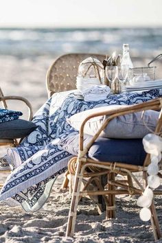 an outdoor table set up on the beach with blue and white linens for blankets