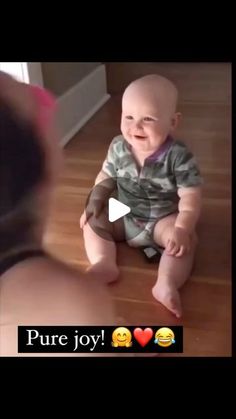 a baby is sitting on the floor and smiling at someone's reflection in the mirror