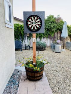 a dart board mounted to the side of a wooden pole next to a potted plant