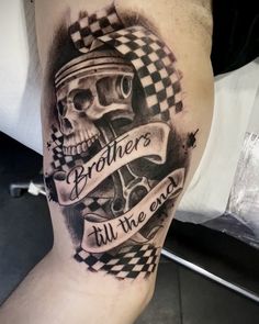 a man with a skull and checkered flag tattoo on his leg that says brothers till the west