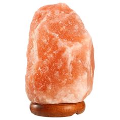 a large orange rock sitting on top of a wooden stand next to a white background