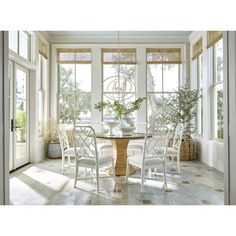 a dining room table surrounded by white chairs and windows with sun shining through the window