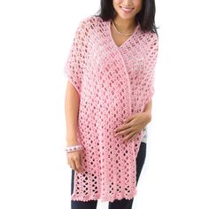 a pregnant woman wearing a pink crochet ponchy with her hands on her belly