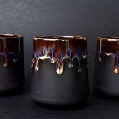 three black and brown vases sitting next to each other on top of a table