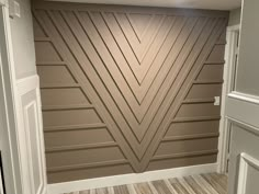 an empty room with wood flooring and a wall painted in brown tones, along with white trim