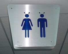 two blue signs on the side of a metal wall with an image of a man and a woman