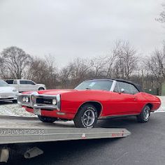 a red car is being towed on a flatbed trailer