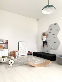 a child climbing on a rock wall in a room with white walls and flooring