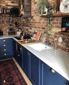 an image of a kitchen setting with blue cabinets and white counter tops on the wall