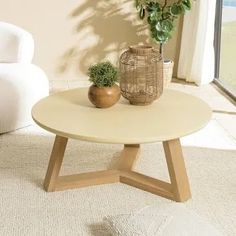 a living room with two white chairs and a coffee table in front of a window