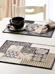 two placemats on a table with a cup and saucer next to each other