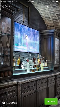 a bar with liquor bottles on it and a large television mounted to the wall behind it