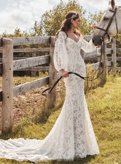 a woman in a white dress standing next to a horse