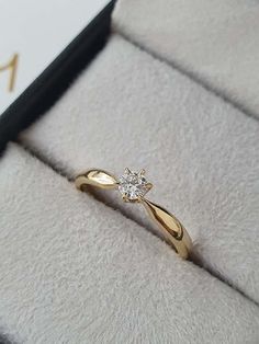 a gold ring with a diamond on it in a gift box that is open to show the inside