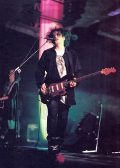 a man standing on top of a stage holding a guitar