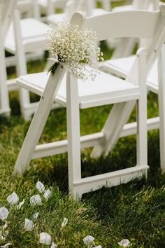 white folding chairs with baby's breath flowers tied to the back are set up for an outdoor ceremony