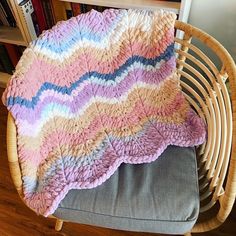 a chair with a blanket on top of it next to a bookshelf filled with books