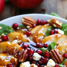 a white bowl filled with apples, cheese and pecans on top of a wooden table