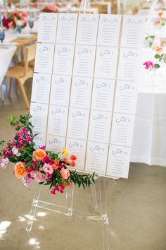 an easer with seating cards on it and flowers in the center is set up for a wedding reception