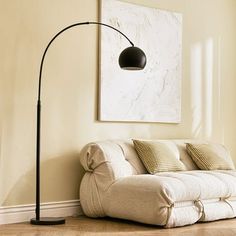 a living room with a white couch and a black floor lamp in it's corner