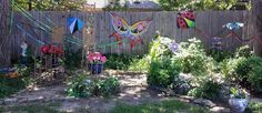 an outdoor garden with flowers and butterflies on the fence