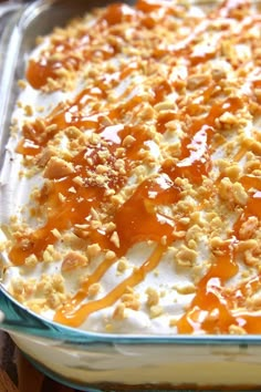 a casserole dish is covered in caramel sauce and whipped cream, with walnuts on top